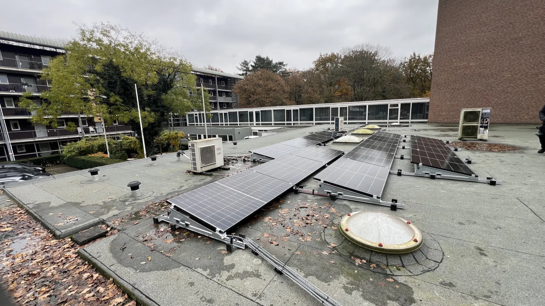 Zonnepanelen op het platte dak aan de Bart Crumstraat in Heelsum, met het woongebouw op de achtergrond
