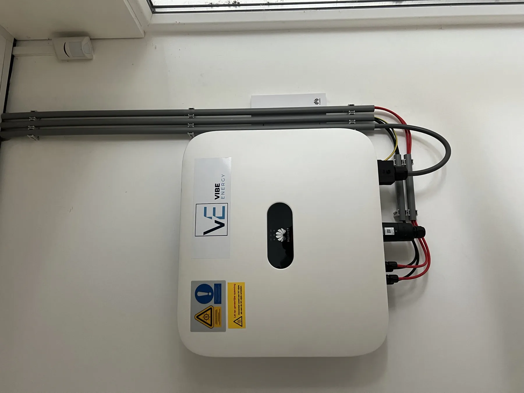 De omvormer van Vibe Energy aan de wand, met bekabeling