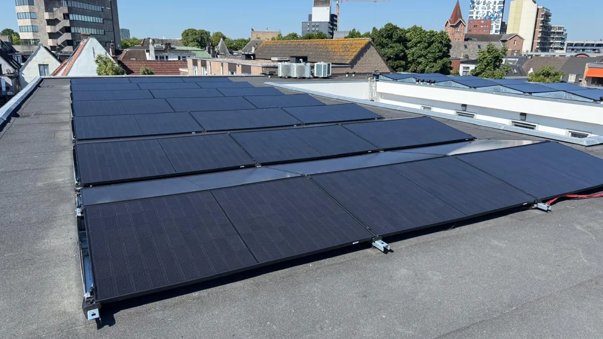 Zonnepanelen op het platte dak aan de Piersonstraat in Nijmegen, met de stad op de achtergrond