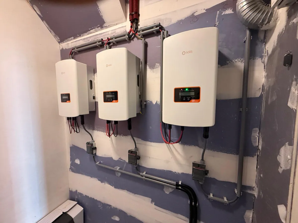 Drie omvormers naast elkaar aan de wand, met bekabeling