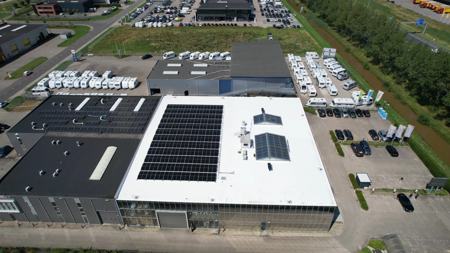 Luchtfoto van bedrijfspand Ratio 16 in Duiven met een zonnedak en het parkeerterrein ernaast