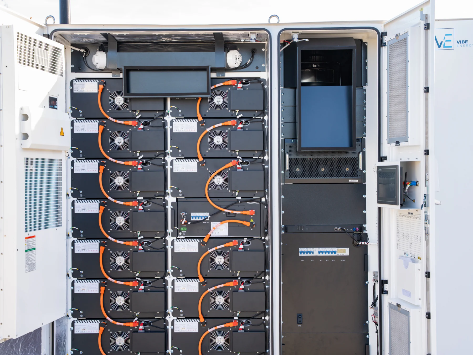 Geopende batterijkast van Vibe Energy met batterijmodules, oranje DC-bekabeling en de regel- en omvormerkast ernaast