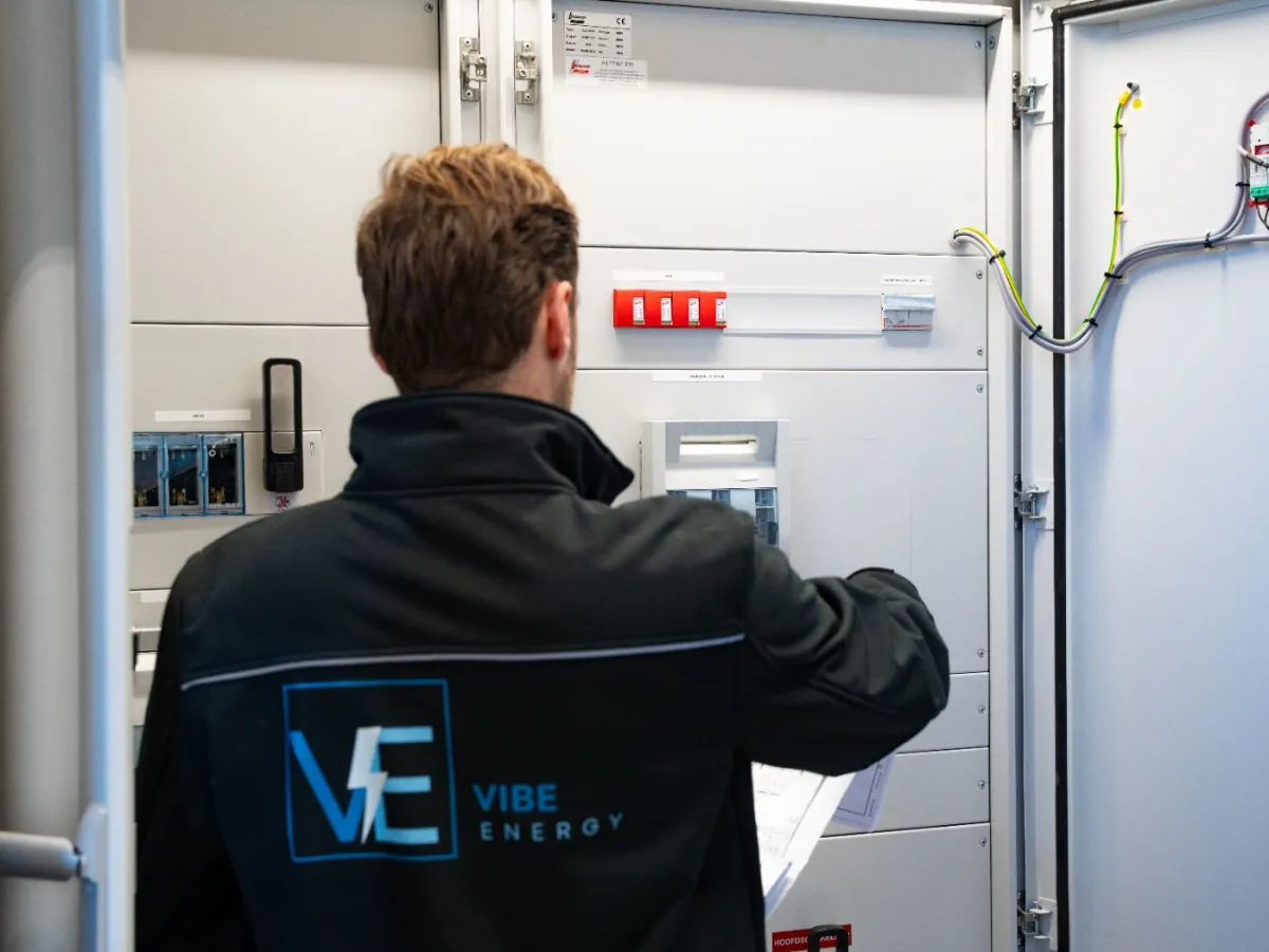 Monteur van Vibe Energy met werktekening in de hand bij een geopende elektrische verdeelkast
